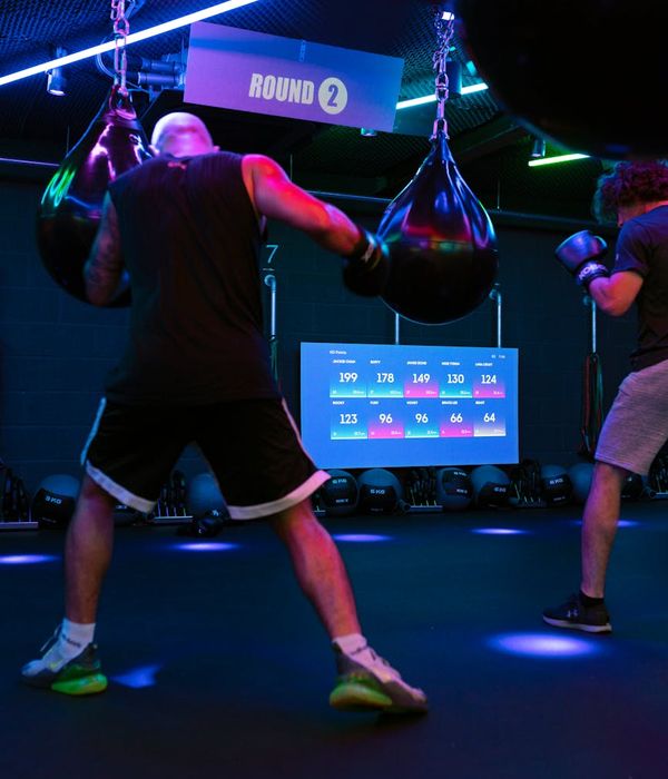 Man performing a controlled strength exercise in a dark studio with neon accents.